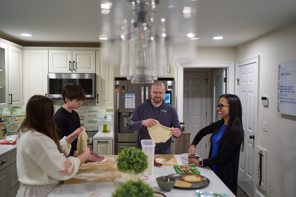 Ruth Wilson, right, who has lupus, makes pizzas with her husband, Jim, and their children at their home, Sunday, Jan. 12, 2025, in Littleton, Mass. (AP Photo/David Goldman)