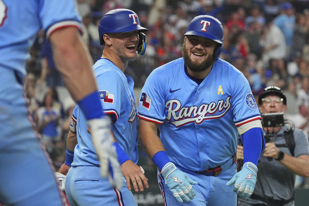 Texas Rangers' Jake Burger, front right, and Josh Jung celebrate after scoring on a Burger home run during the sixth inning of a baseball game against the Houston Astros, Sunday, Sept. 7, 2025, in Arlington, Texas. (AP Photo/LM Otero)