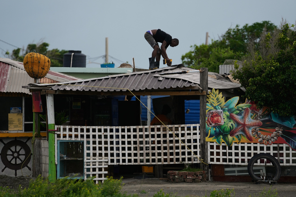 A man fortifies a roof ahead of the forecast arrival of Hurricane Melissa in Kingston, Jamaica, Sunday, Oct. 26, 2025. (AP Photo/Matias Delacroix)