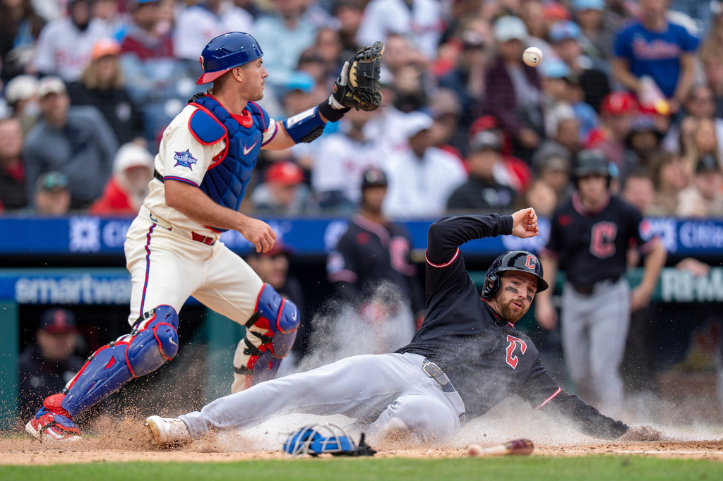 Cleveland Guardians' Daniel Schneemann, right, slides into home on a single hit by teammate Steven Kwan as Philadelphia Phillies catcher J.T. Realmuto, left, waits for the ball during the fifth inning of a baseball game, Sunday, May 24, 2026, in Philadelphia. (AP Photo/Chris Szagola)