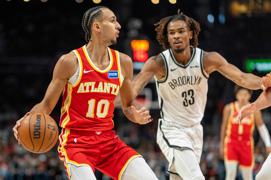 Atlanta Hawks forward Zaccharie Risacher (10), left, attempts to pass the ball against Brooklyn Nets center Nic Claxton (33) during the first half of an NBA basketball game, Sunday, Feb. 22, 2026, in Atlanta. (AP Photo/Erik Rank)