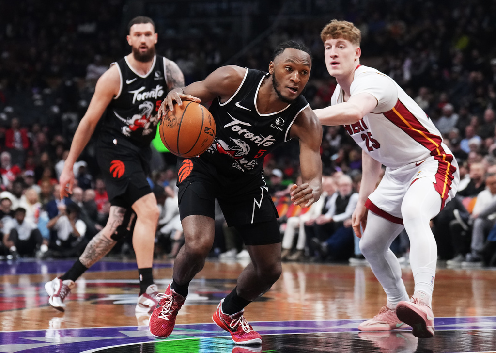 Toronto Raptors' Immanuel Quickley (5) drives past Miami Heat's Kasparas Jakucionis (25) during the first period of an NHL game in Ottawa, Thursday, April 9, 2026. (Adrian Wyld/The Canadian Press via AP)