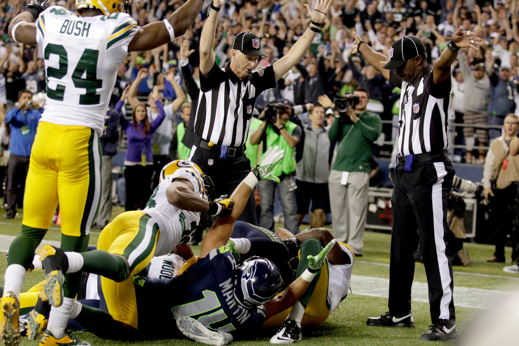 FILE - Officials signal a touchdown by Seattle Seahawks wide receiver Golden Tate, obscured, on the last play of an NFL football game against the Green Bay Packers, Monday, Sept. 24, 2012, in Seattle. (AP Photo/Stephen Brashear, File)