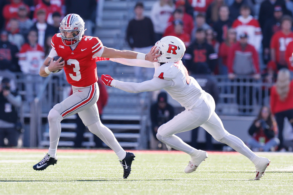 Ohio State quarterback Lincoln Kienholz, left, stiff arms Rutgers linebacker Sam Robinson during the second half of an NCAA college football game, Saturday, Nov. 22, 2025, in Columbus, Ohio. (AP Photo/Jay LaPrete)