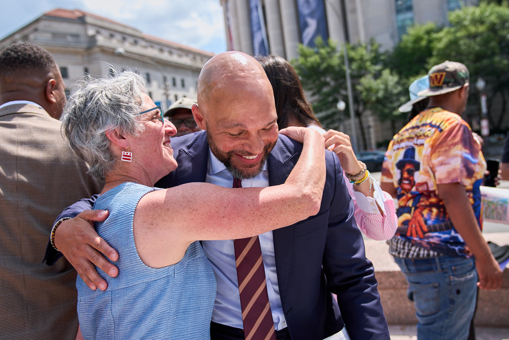 Congressional delegate candidate Robert White, is hugged by District of Columbia Councilmember Elissa Silverman, left, after attending a news conference at Freedom Plaza in Washington, Monday, Aug. 24, 2026. (AP Photo/Jacquelyn Martin)