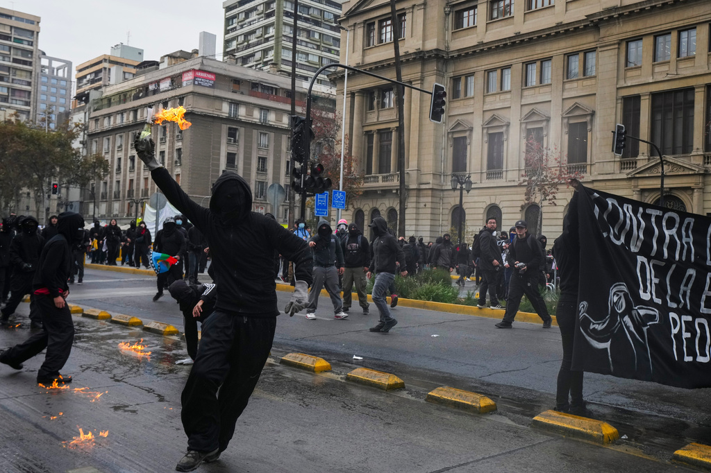 A student throws a Molotov cocktail at police during a protest against the government's proposal to lower the education budget, in Santiago, Chile, Wednesday, June 3, 2026. (AP Photo/Esteban Felix)