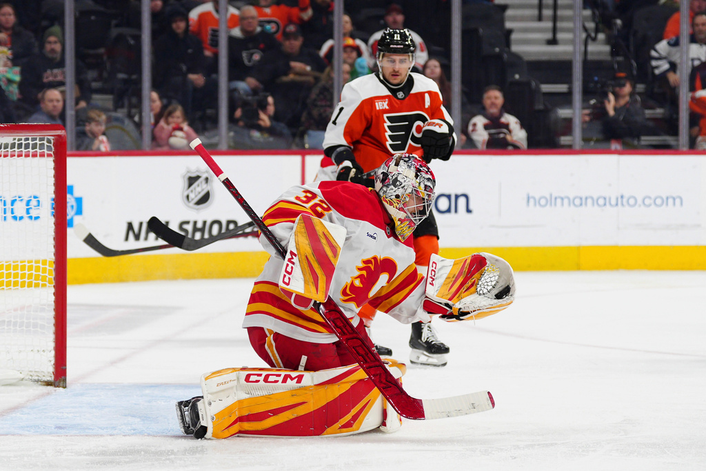 Calgary Flames goaltender Dustin Wolf (32) makes a glove-save during the second period of an NHL hockey game against the Philadelphia Flyers, Sunday, Nov. 2, 2025, in Philadelphia. (AP Photo/Derik Hamilton)