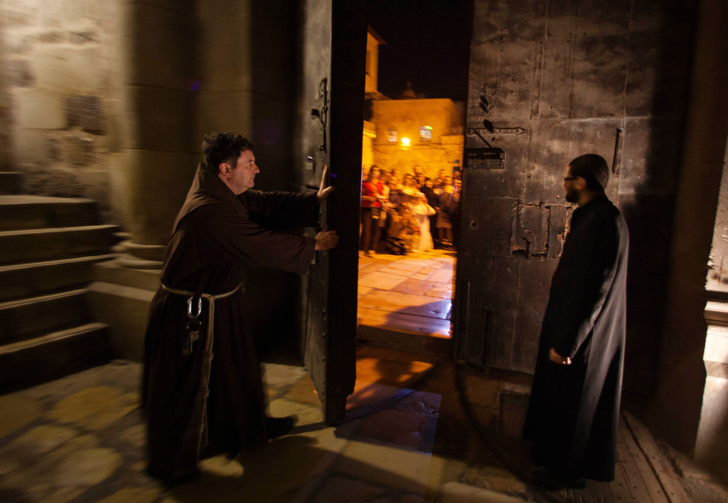 FILE - A priest closes the door to the Holy Sepulcher church for the night in Jerusalem on Thursday, May 17, 2012. (AP Photo/Dusan Vranic, File)