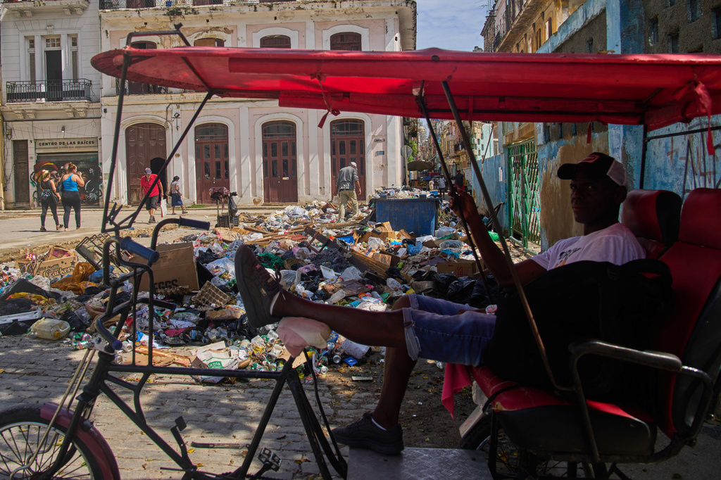 A bicycle taxi driver waits for customers, next to a pile of trash in Havana, Cuba, Monday, June 1, 2026. (AP Photo/Ramon Espinosa)