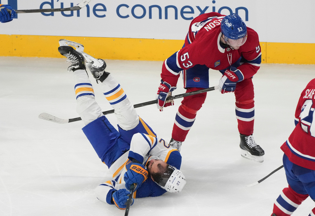 Buffalo Sabres' Jordan Greenway (12) is upended by Montreal Canadiens' Noah Dobson (53) during the third period of an NHL hockey game in Montreal on Thursday, Jan. 22, 2026. (Christinne Muschi/The Canadian Press via AP)