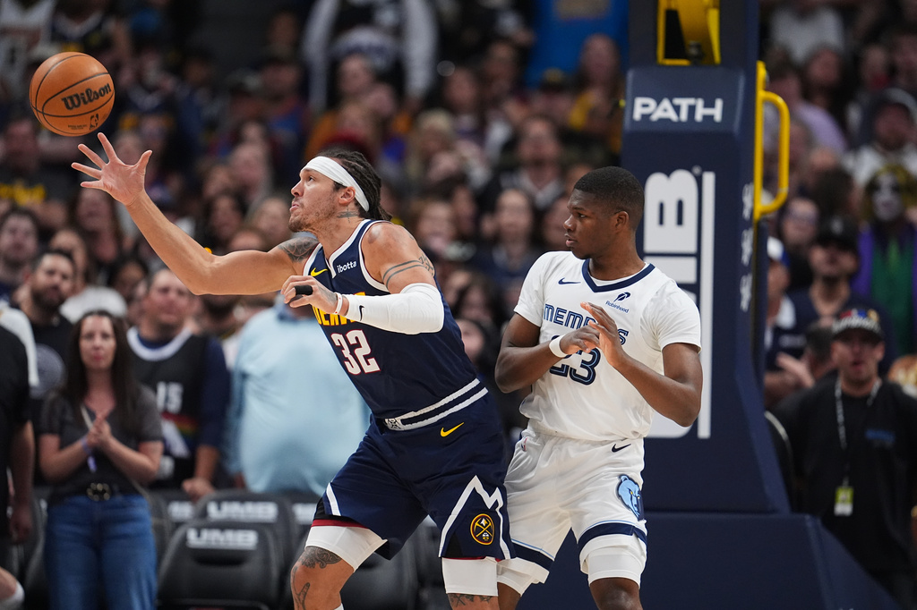 Denver Nuggets forward Aaron Gordon, left, pulls in a loose ball as Memphis Grizzlies guard Cedric Coward defends in the first half of an NBA basketball game Wednesday, April 8, 2026, in Denver. (AP Photo/David Zalubowski)