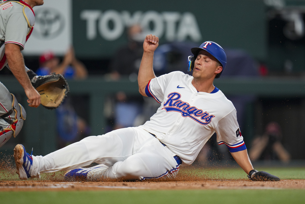 Texas Rangers' Corey Seager slides into home while scoring on a single by teammate Marcus Semien during the first inning of a baseball game against the Philadelphia Phillies Saturday, Aug. 9, 2025, in Arlington, Texas. (AP Photo/Julio Cortez)