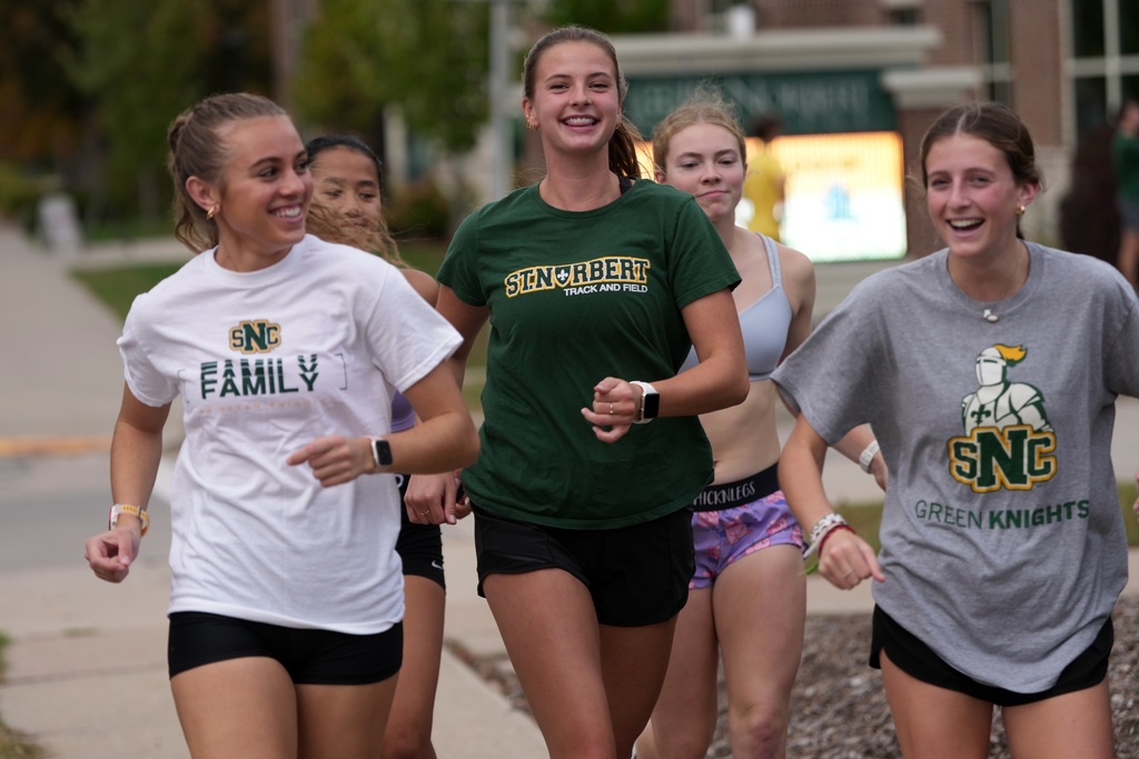 Cross country runner Madison DeCleene, center, runs with her St. Norbert College teammates, Friday, Oct. 17, 2025, in De Pere, Wis. (AP Photo/Morry Gash)