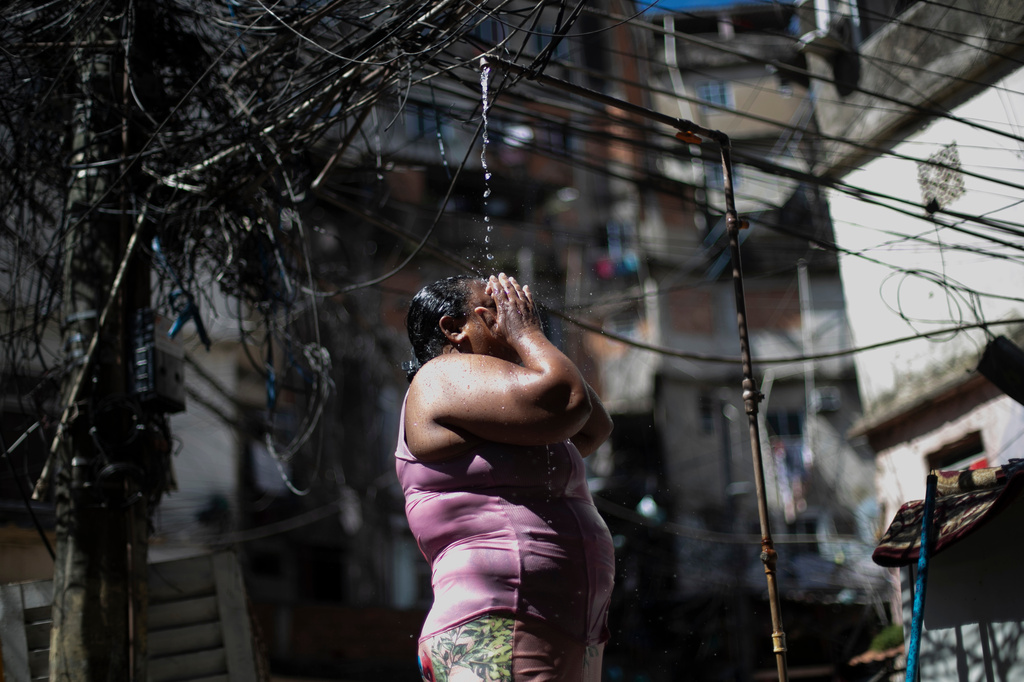 FILE - Kelly Cristina da Cruz cools off in a public shower in the Rocinha favela amid a heat wave in Rio de Janeiro, Jan. 15, 2026. (AP Photo/Bruna Prado, File)