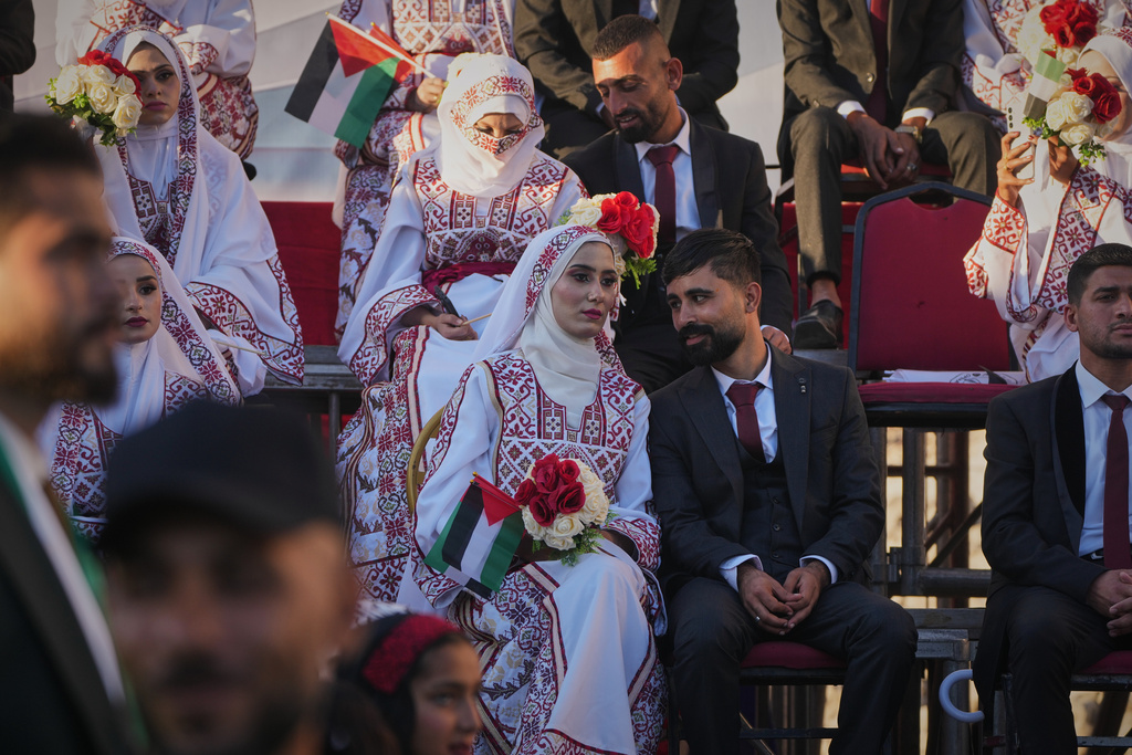 Palestinian couple Hikmat Lawwa and Eman Lawwa, center, join other newlyweds in a mass wedding ceremony at Hamad City in Khan Younis, southern Gaza Strip, Tuesday, Dec. 2, 2025. (AP Photo/Abdel Kareem Hana)