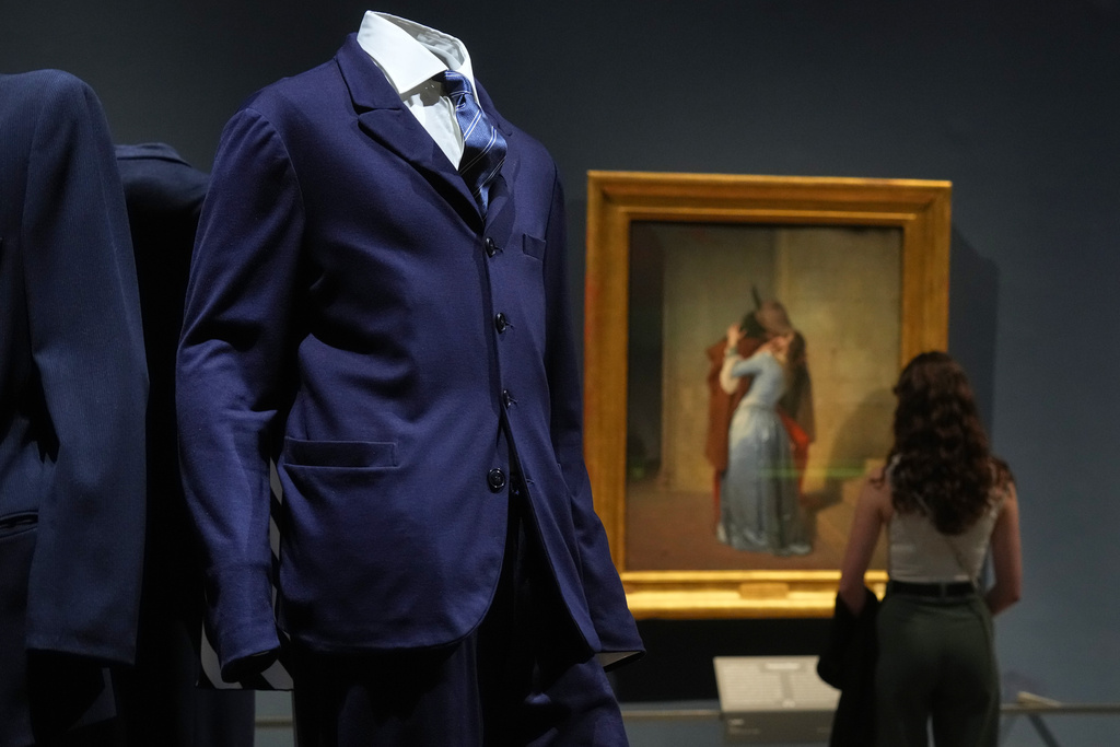 Giorgio Armani's creations are backdropped by the painting by Francesco Hayez titled "The Kiss", during the exhibition "Giorgio Armani - 50 Years" opened to the public at the Pinacoteca di Brera in Milan, Italy, Wednesday, Sept. 24 2025. (AP Photo/Antonio Calanni)