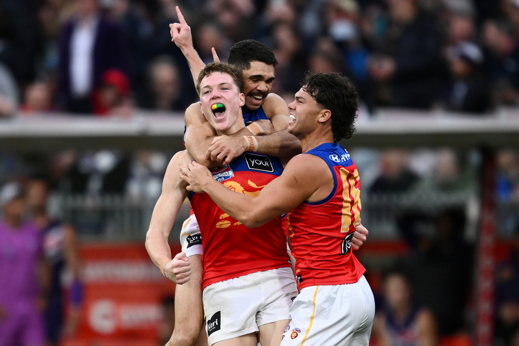 Brisbane Lions players Logan Morris, center, Charlie Cameron, rear, and Cam Rayner celebrate their win over the Fremantle Dockers in the Australian Football League grand final in Melbourne, Australia Saturday, Sept. 26, 2026. (Joel Carrett/AAP Image via AP)