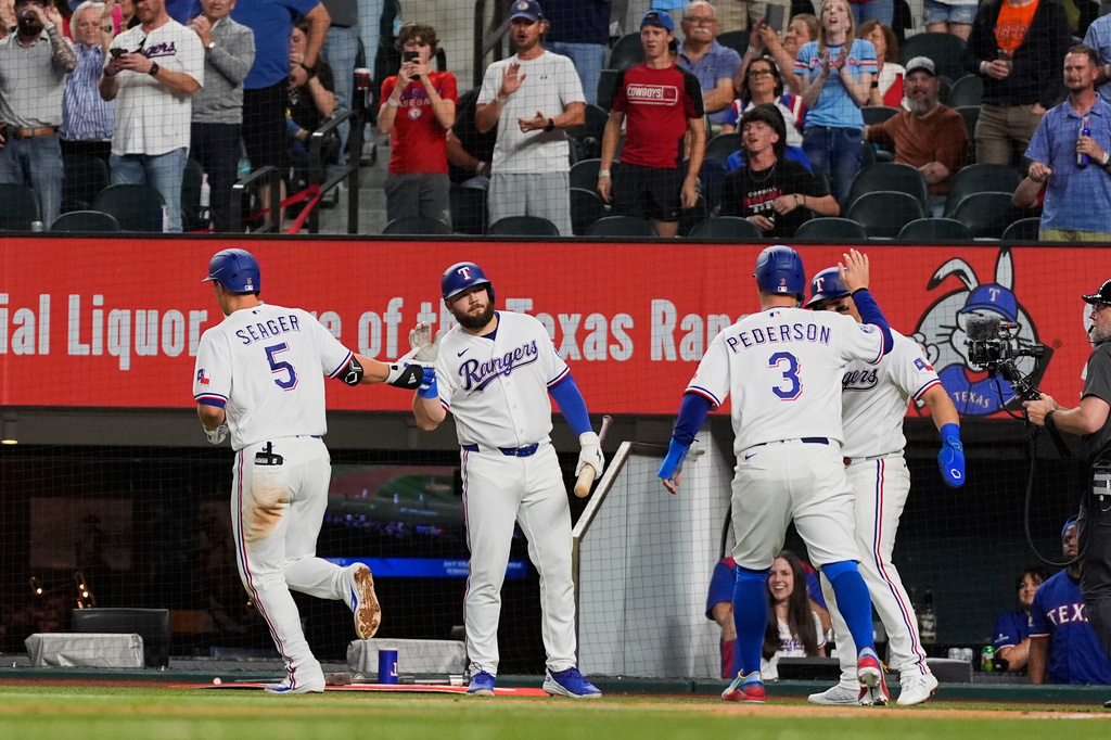 Texas Rangers' Corey Seager (5), Jake Burger, center rear, Joc Pederson (3) and Alejandro Osuna, right rear, celebrate Seager's three-run home run in the fourth inning of a baseball game against the Pittsburgh Pirates Thursday, April 23, 2026, in Arlington, Texas. (AP Photo/Tony Gutierrez)