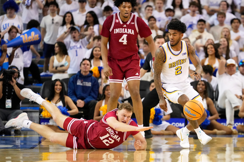 Indiana forward Tucker DeVries, left, dives for the ball as UCLA guard Donovan Dent, right, takes it while forward Sam Alexis watches during the first half of an NCAA college basketball game, Saturday, Jan. 31, 2026, in Los Angeles. (AP Photo/Mark J. Terrill)