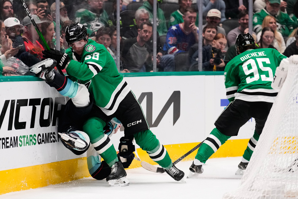 Seattle Kraken center Berkly Catton, left, is slammed against the boards by Dallas Stars' Thomas Harley (55) as Matt Duchene (95) skates past in the second period of an NHL hockey game in Dallas, Wednesday, Feb. 25, 2026. (AP Photo/Tony Gutierrez)
