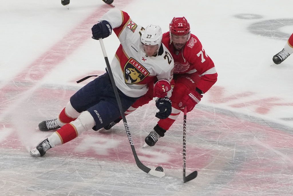 Florida Panthers center Eetu Luostarinen (27) and Detroit Red Wings defenseman Justin Faulk (72) go after the puck during the second period of an NHL hockey game, Tuesday, March 10, 2026, in Sunrise, Fla. (AP Photo/Marta Lavandier)