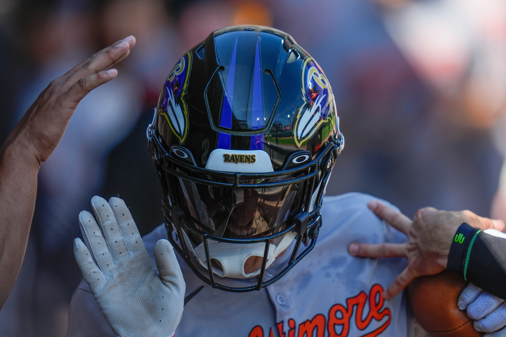 Baltimore Orioles' Dylan Beavers (12) wears a Ravens football helmet and carries a football as he celebrates after hitting a two-run home run during the fourth inning of a baseball game against the Chicago White Sox, Wednesday, Sept. 17, 2025, in Chicago. (AP Photo/Erin Hooley)