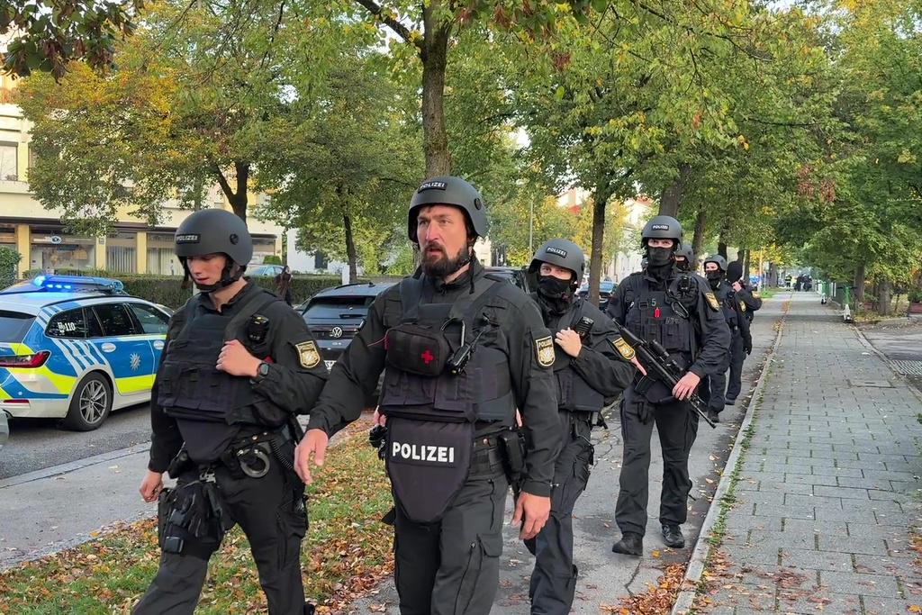 Police officers walk along a footpath after a fire in a detached house in Munich, Germany, Wednesday, Oct. 1, 2025. (Roland Freund/dpa via AP)