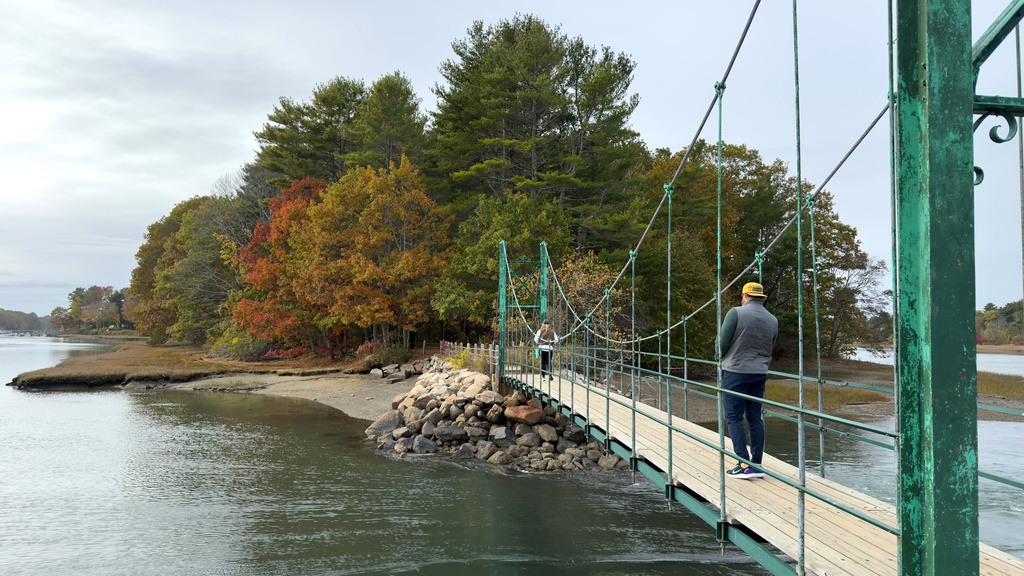 Visitors walk on Wiggly Bridge in York, Maine, on their way to view fall foliage on Tuesday, Oct. 14, 2025. (AP Photo/Rodrique Ngowi)