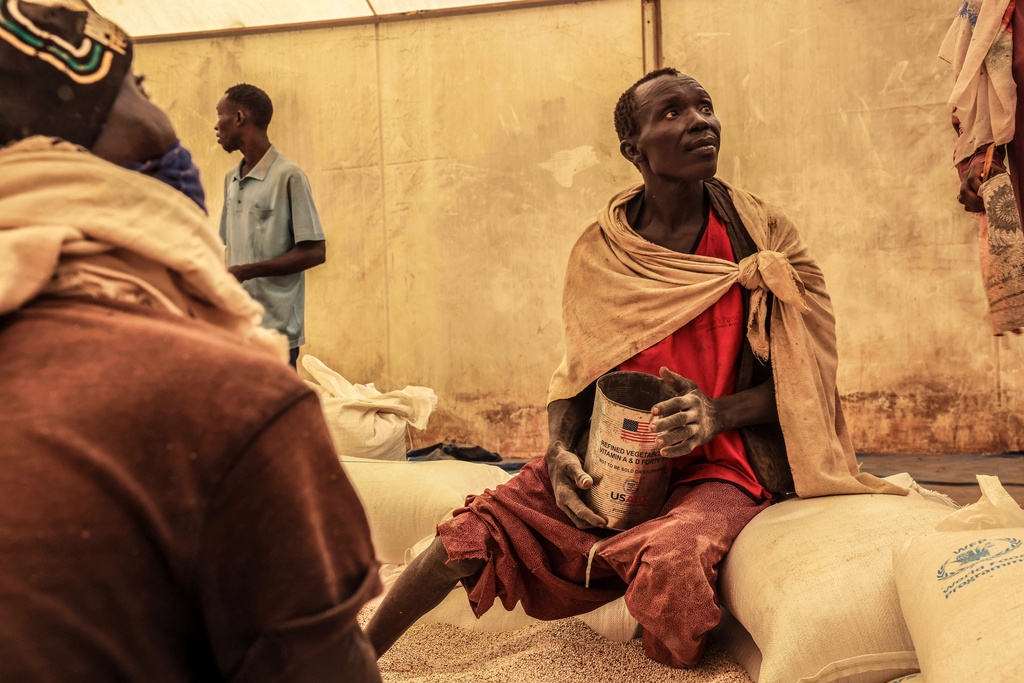 FILE - A man scoops up portions of wheat to be allocated to each waiting family after distribution by the U.N. World Food Programme (WFP) in the Gendrassa Refugee Camp, Maban, South Sudan, Wednesday, Aug. 20, 2025. (AP Photo/Caitlin Kelly, File)
