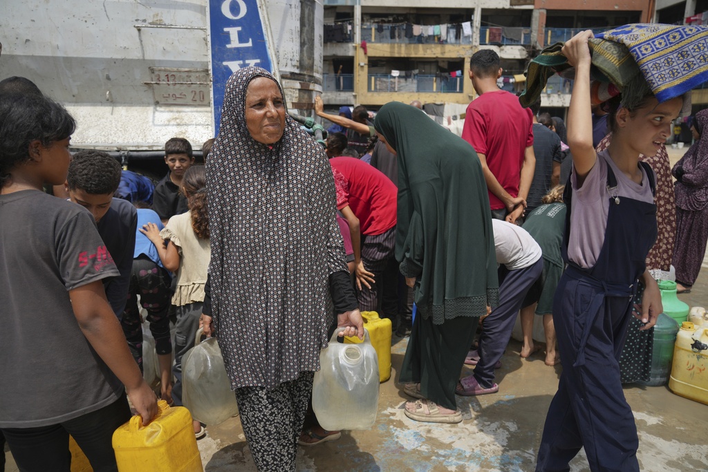 In the summer heat, Enaam Al Majdoub carries a jerrycan after collecting water from a distribution point in Gaza City, Tuesday, Aug. 12, 2025. (AP Photo/Jehad Alshrafi)