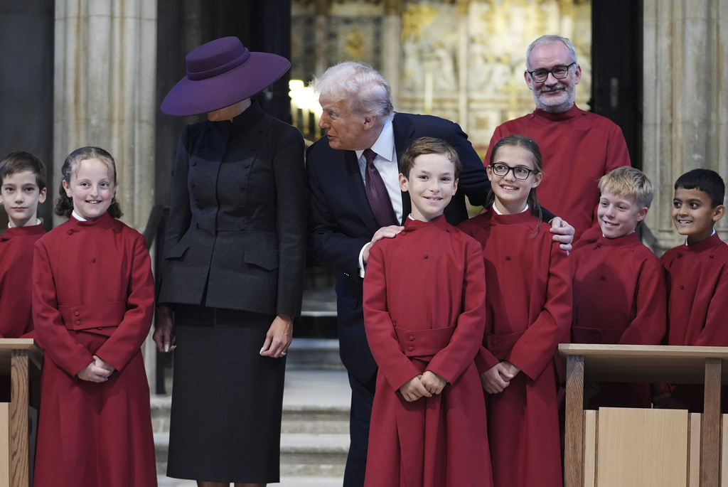 President Donald Trump and first lady Melania Trump pose with a childrens choir as they receive a tour of St. George's Chapel at Windsor Castle, Windsor, England, Wednesday, Sept. 17, 2025. (AP Photo/Evan Vucci, Pool)