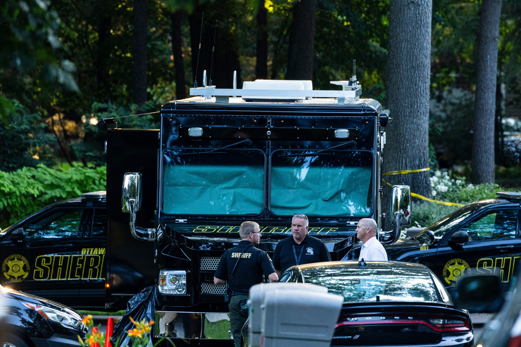Law enforcement officials gather to investigate a fatal house fire on Friday, July 24, 2026, in Grand Haven Township, Mich. Ottawa County Sheriff's Office said six children and two adults were found dead in a "suspicious" house fire. (Joel Bissell/Kalamazoo Gazette via AP)