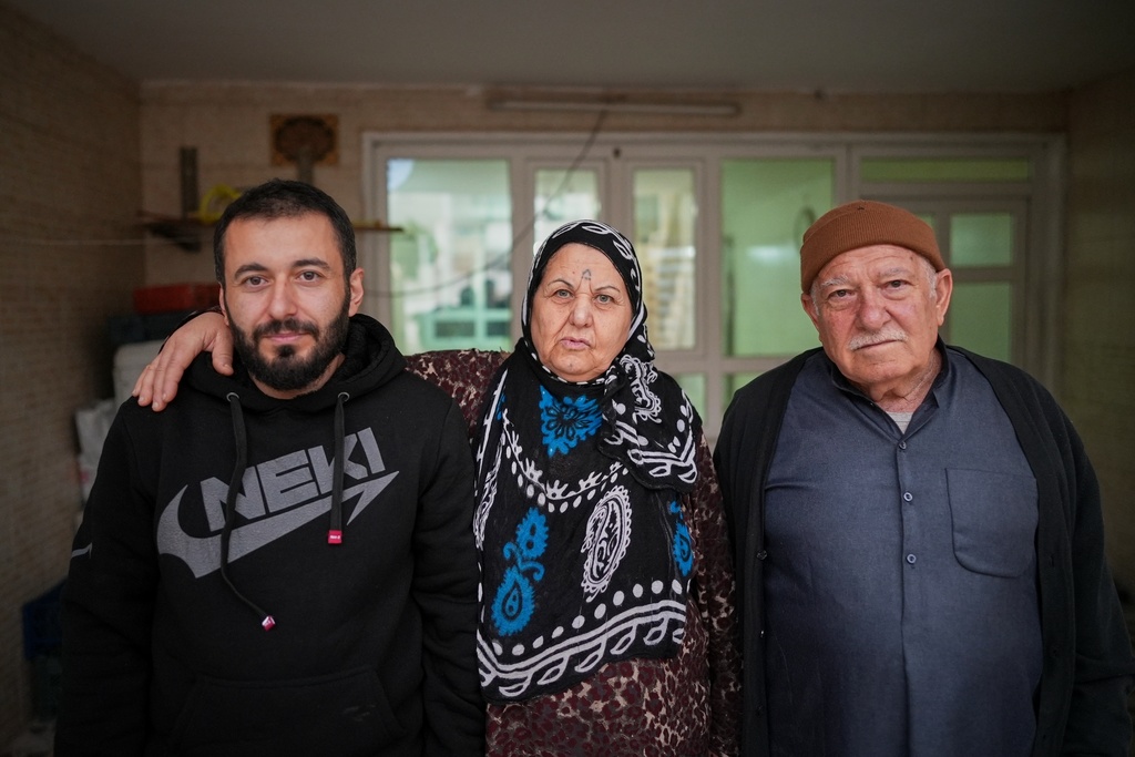 Syrian refugee Mohammed Dawood, 30, left, poses for a photo with his parents, Hayat Fatah, 65, center, and Abdulilah Amin Dawoud, 73, at their home in Irbil, Iraq, Nov. 16, 2025. (AP Photo/Farid Abdulwahed)