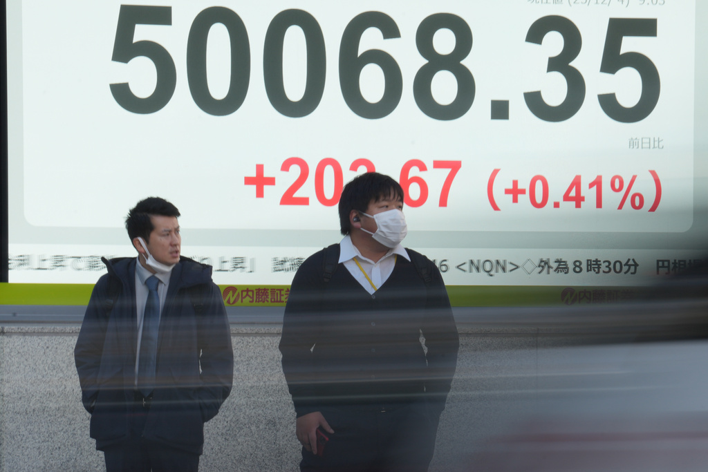 People stand in front of an electronic stock board showing Japan's Nikkei index at a securities firm Thursday, Dec. 4, 2025, in Tokyo. (AP Photo/Eugene Hoshiko)