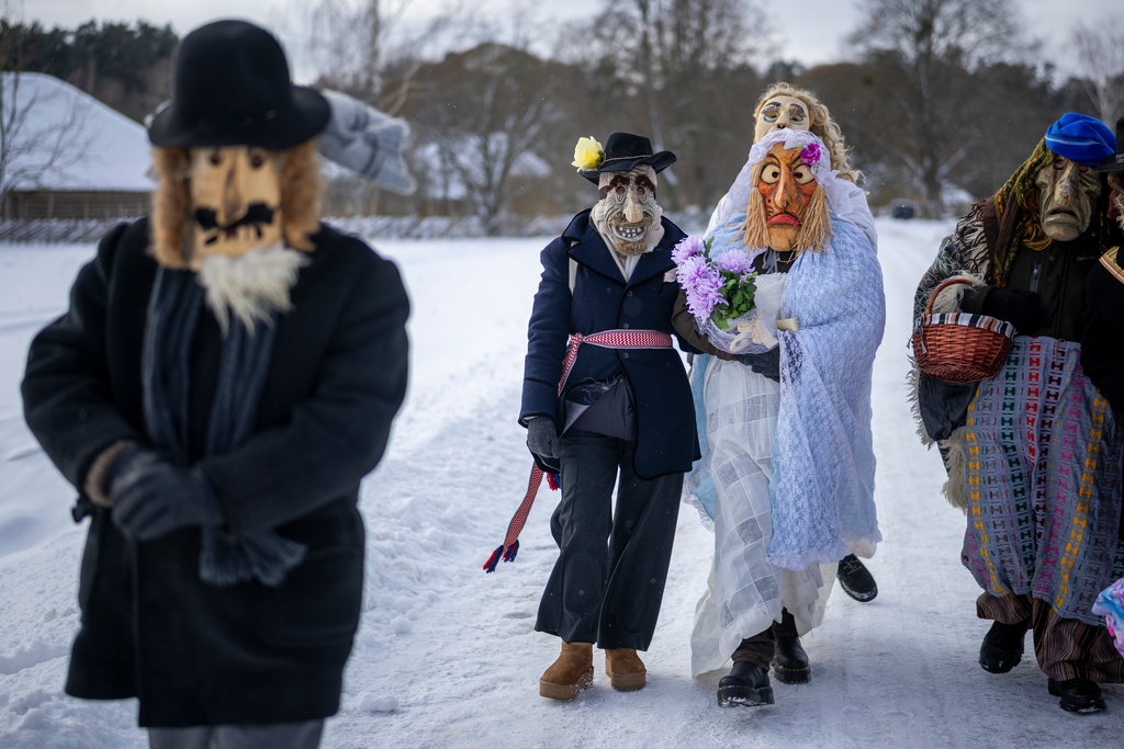 Performers dressed as newlyweds take part in Shrovetide celebrations in the village of Rumsiskes, some 89 kilometers (56 miles) north of Vilnius, Lithuania, Saturday, Feb. 14, 2026. (AP Photo/Mindaugas Kulbis)