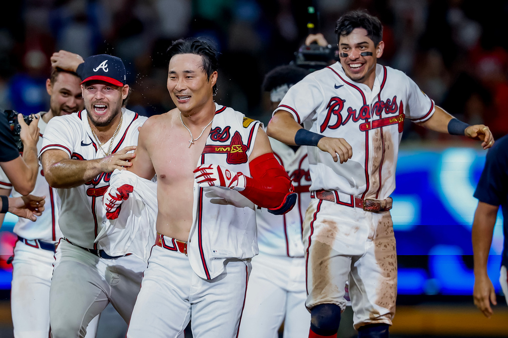 Atlanta Braves pinch-hitter Ha-Seong Kim, center, is mobbed by teammates Victor Mederos, left, and Mauricio Dubón, right, after Kim hit a game-winning RBI single against the Los Angeles Dodgers during the ninth inning of a baseball game, Wednesday, Aug. 26, 2026, in Atlanta. (AP Photo/Erik S. Lesser)