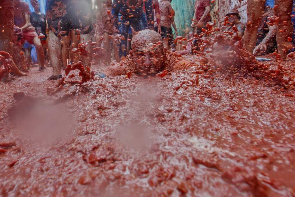 A man throws himself over a pool of tomatoes during the annual "Tomatina" tomato fight fiesta, in the village of Bunol near Valencia, Spain, Wednesday, Aug. 27, 2025. (AP Photo/Alberto Saiz)