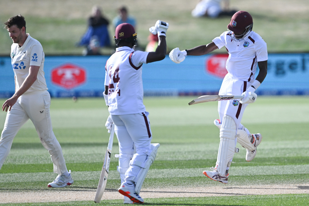 West Indies' Justin Greaves, right, celebrates with teammate Kemar Roach, center, after scoring 200 runs against New Zealand on Day 5 of their cricket test match in Christchurch, New Zealand, Saturday, Dec. 6, 2025. (Andrew Cornaga/Photosport via AP)