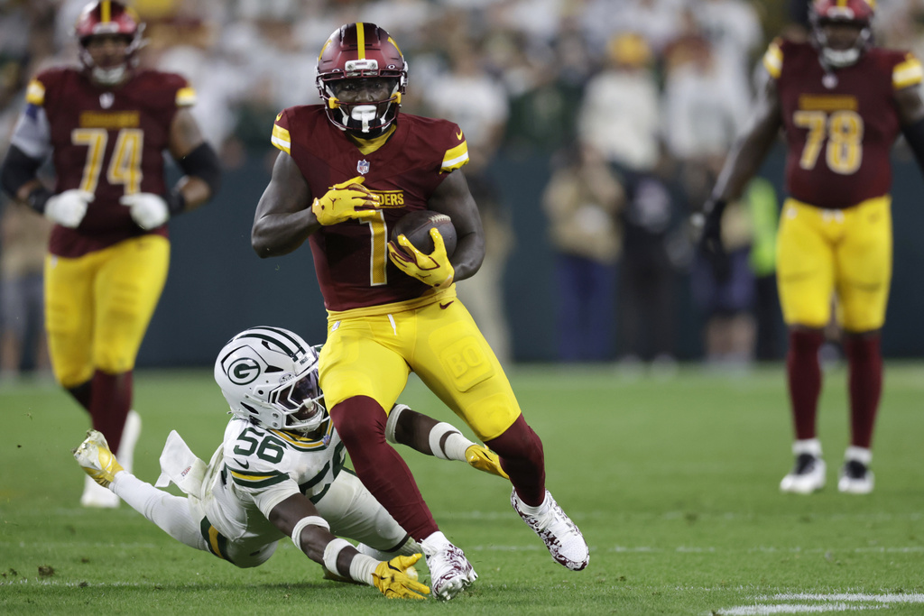 Washington Commanders wide receiver Deebo Samuel (1) catches the ball and runs for a first down as Green Bay Packers linebacker Edgerrin Cooper (56) defends during the second half of an NFL football game Thursday, Sept. 11, 2025, in Green Bay, Wis. (AP Photo/Matt Ludtke)