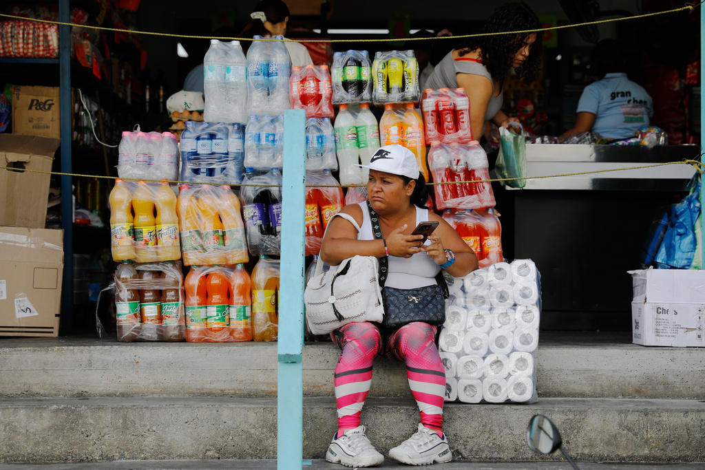 A woman sits in front of a store in the Petare neighborhood of Caracas, Venezuela, Wednesday, Jan. 7, 2026. (AP Photo/Cristian Hernandez)