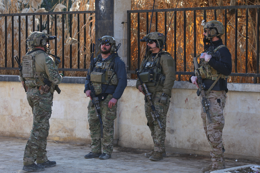 American soldiers from the U.S.-led coalition against the Islamic State group stand guard during a meeting with the U.S.-backed Syrian Democratic Forces in Deir Hafer, Syria, Friday, Jan. 16, 2026. (AP Photo/Baderkhan Ahmad)