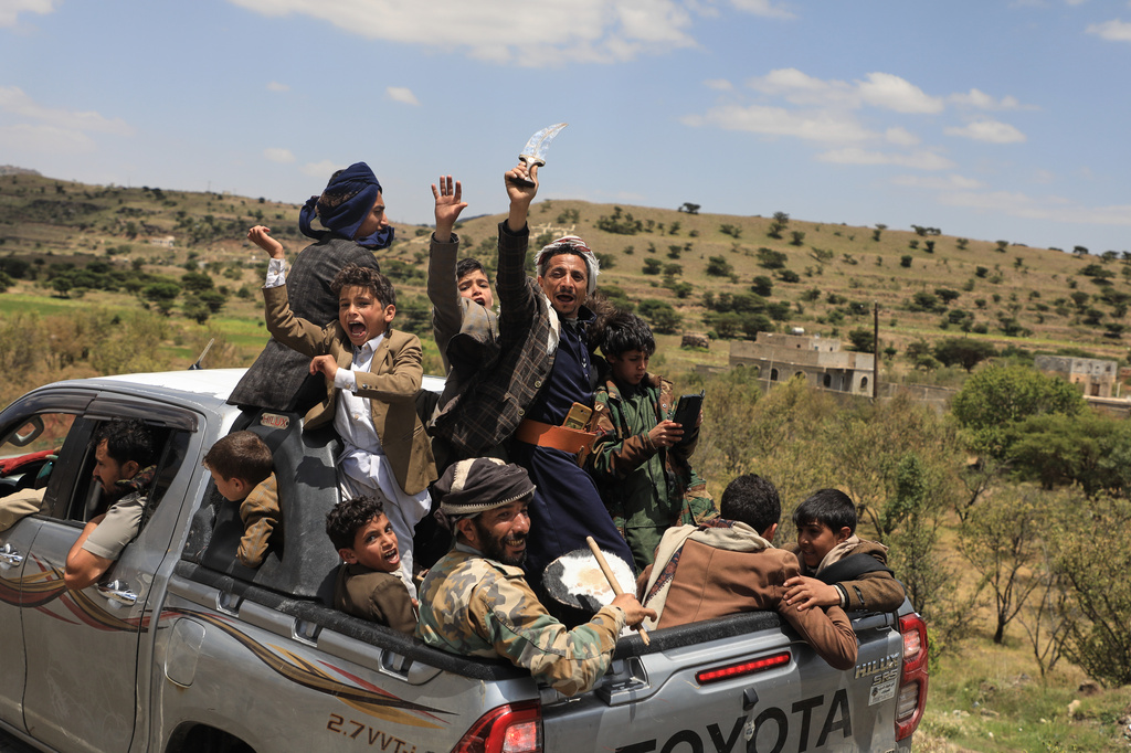 Yemeni civilians celebrate while riding in the back of a pickup truck in the Bani Matar district, Yemen, Saturday, Sept. 12, 2026, as they follow a convoy carrying Houthi prisoners freed in Mokha on its way to Sanaa following the Houthi takeover of the southern Red Sea port city. (AP Photo/STR)