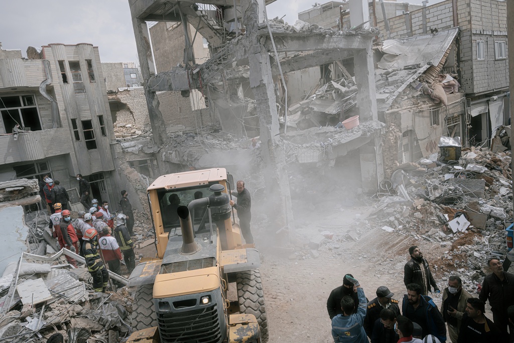 First responders use an excavator to clean the debris and search for victims at a residential building hit in an overnight strike during the U.S.-Israeli military campaign in Tabriz, East Azerbaijan Province, northwestern Iran, Tuesday, March 24, 2026. (AP Photo/Matin Hashemi)