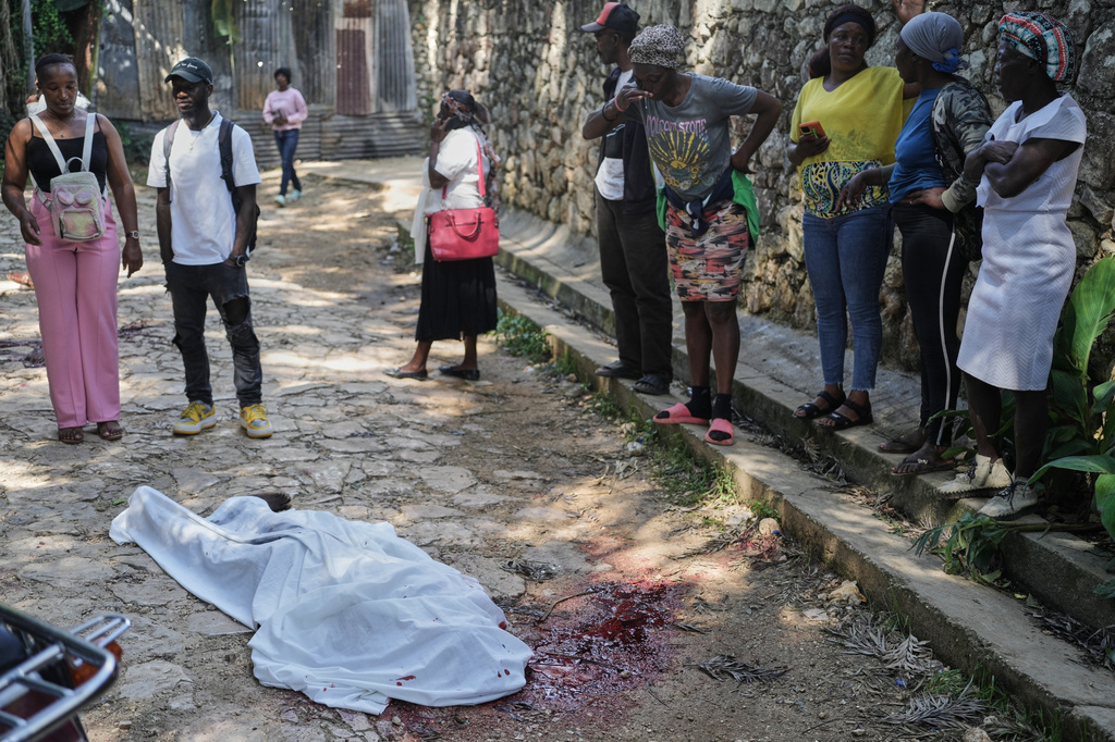 People look at the body of a person who was killed during a gang attack in the Kenscoff neighborhood of Port-au-Prince, Haiti, Monday, Aug. 24, 2026. (AP Photo/Odelyn Joseph)