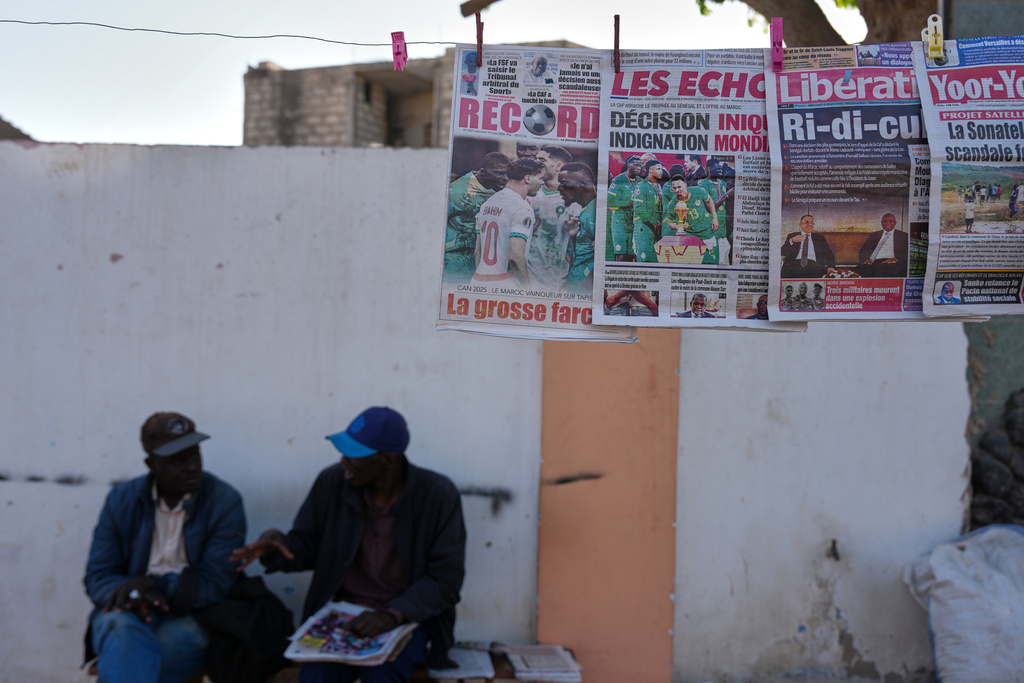 Front pages of newspapers reporting on the Confederation of African Football decision stripping the Senegal national football team of their Africa Cup of Nations title and awarding it to the Morocco national football team in Dakar, Senegal, Wednesday, March 18, 2026. (AP Photo/Misper Apawu)