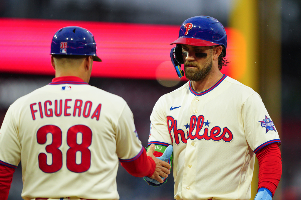 Philadelphia Phillies' Bryce Harper, right, greets first base coach Paco Figueroa (38) after hitting a single during the fourth inning of a baseball game against the Cleveland Guardians, Saturday, May 23, 2026, in Philadelphia. (AP Photo/Derik Hamilton)