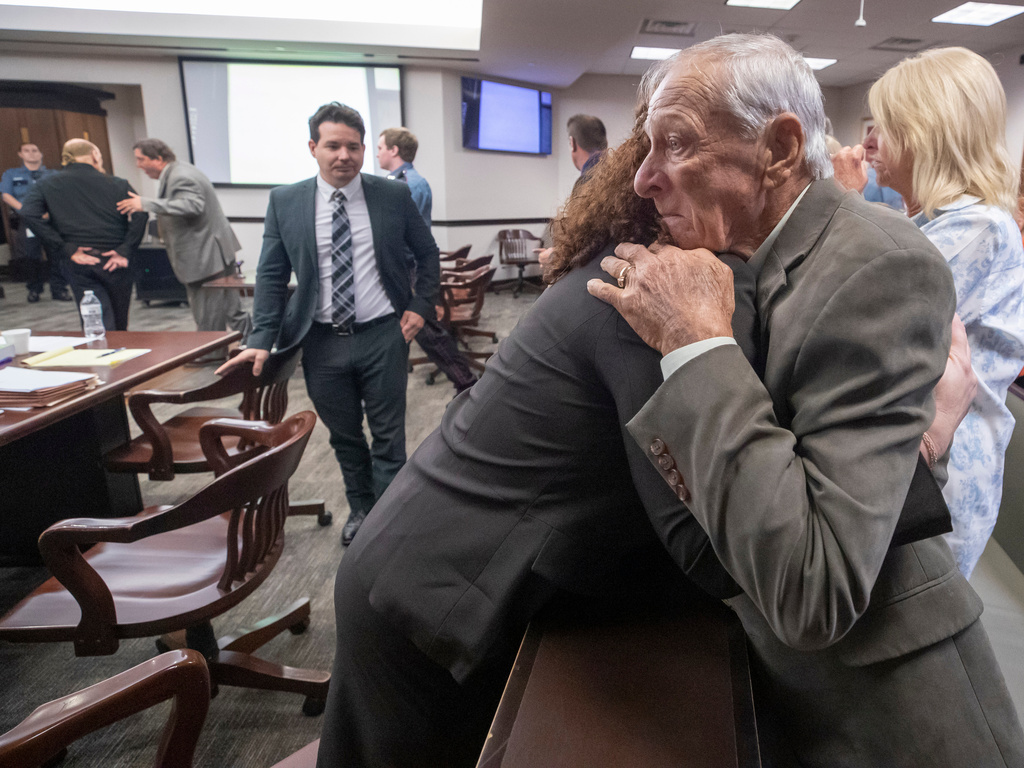 Tim Miller, father of Laura Miller, embraces Galveston County Chief Assistant District Attorney Kate Willis, as James Dolphs Elmore Jr., far left, walks in handcuffs from the courtroom after he was found guilty of manslaughter in Galveston, Texas, Wednesday, Sept. 2, 2026. (Stuart Villanueva/The Galveston County Daily News via AP, Pool)