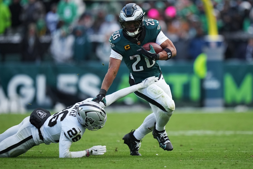 Philadelphia Eagles running back Saquon Barkley (26) runs with the ball past Las Vegas Raiders cornerback Darien Porter (26) during the second half of an NFL football game Sunday, Dec. 14, 2025, in Philadelphia. (AP Photo/Matt Slocum)