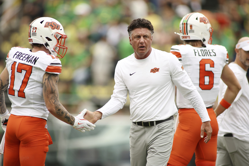 Oklahoma State head coach Mike Gundy slaps hands with wide receiver Gavin Freeman (17) during warmups before an NCAA college football game against Oregon, Saturday, Sept. 6, 2025, in Eugene, Ore. (AP Photo/Lydia Ely)