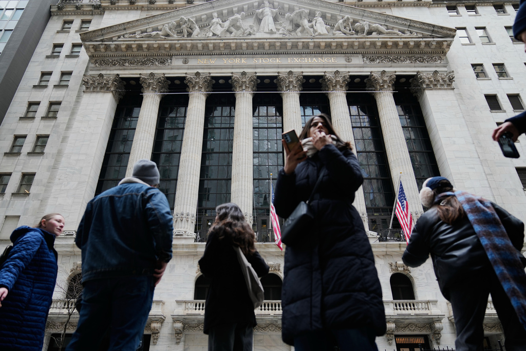 Pedestrians mill about outside the New York Stock Exchange in New York, Friday, March 6, 2026. (AP Photo/Seth Wenig)
